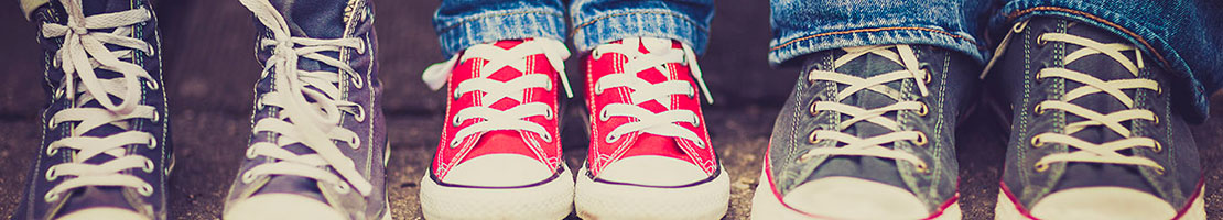 Large and small tennis shoes of teens and children lined up